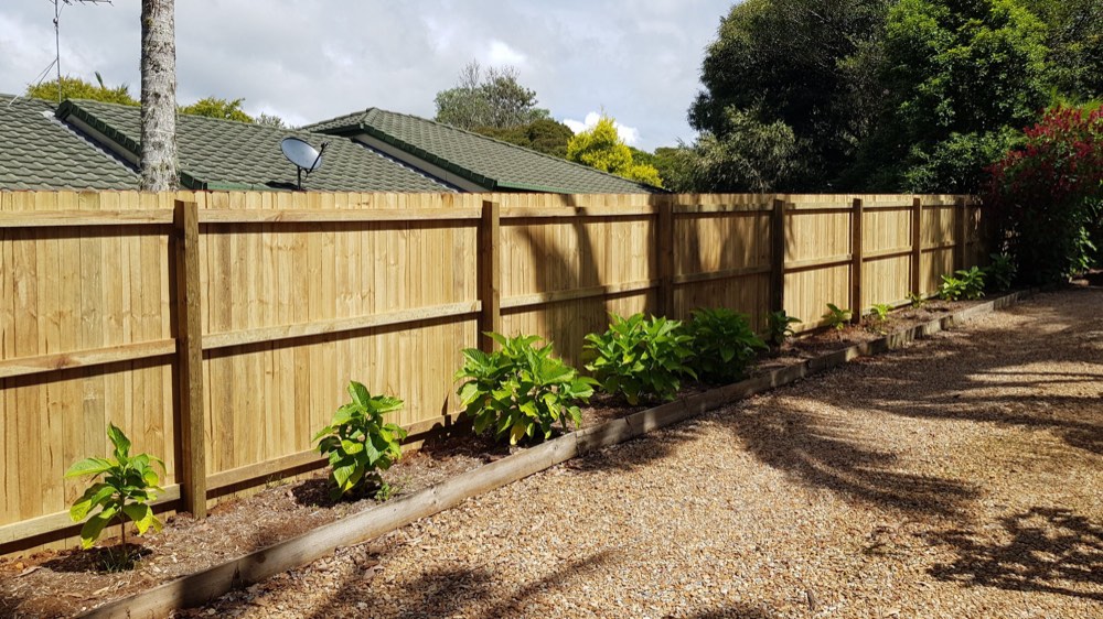 Treated pine paling fence along a garden bed